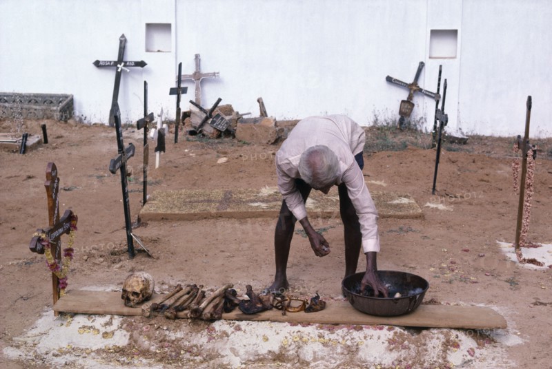 INDIA, Goa , Man in a cemetary cleaning bones that have been removed from a family grave which will be replaced to make room for the next family member