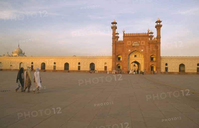 PAKISTAN, Punjab, Lahore , Badshahi Mosque attached to the Royal Fort.  Built c.1672-3 during the reign of Mughal emperor Aurangzeb.  Visitors in courtyard in foreground.