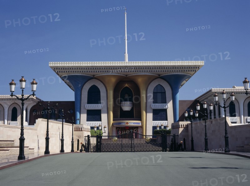 OMAN, Muscat , Sultans Palace, "Brightly colored architecture seen across lampost lined bridge,"