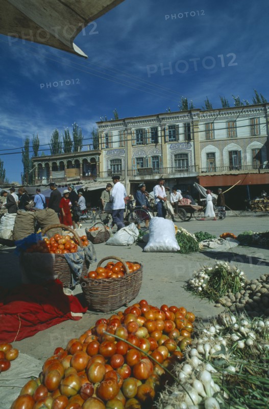 CHINA, Xinjiang, Kashgar, Vegetables for sale on the street in front of three storey buildings at the Sunday Market
