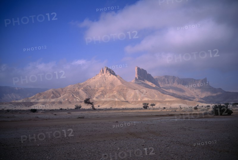 SAUDI ARABIA, Eastern Province, Howtah, Desert landscape with triangular rock formation and pinnacles in sunlight