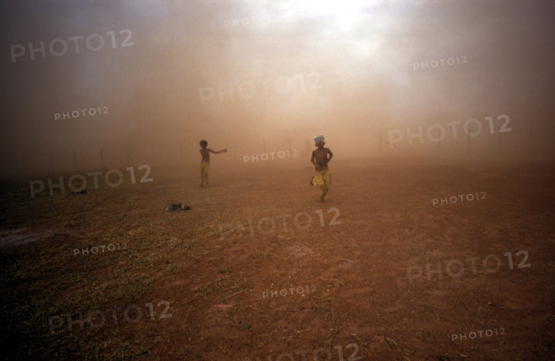 CAMBODIA, Military, Two children emerging from the dust cloud from a M: 26 Helicopter.