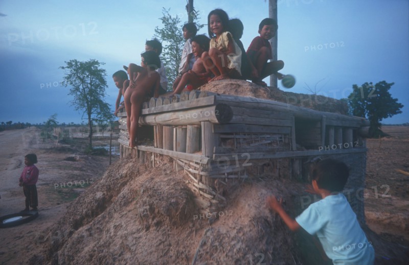 CAMBODIA, Phnom Pehn, Children playing on pillbox gun shelter made of wood and packed earth.