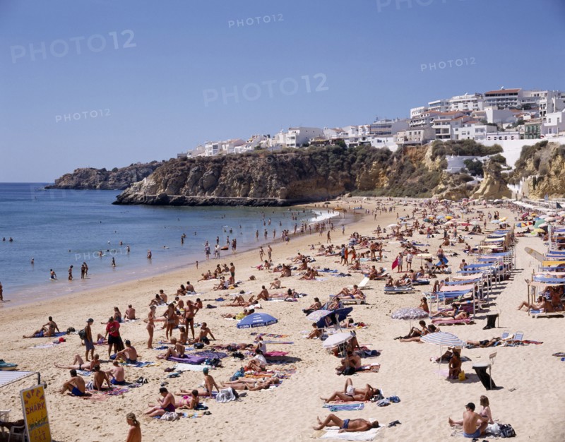 PORTUGAL, Algarve, Albufeira, View along the beach from above with sunbathers and the houselined headland beyond