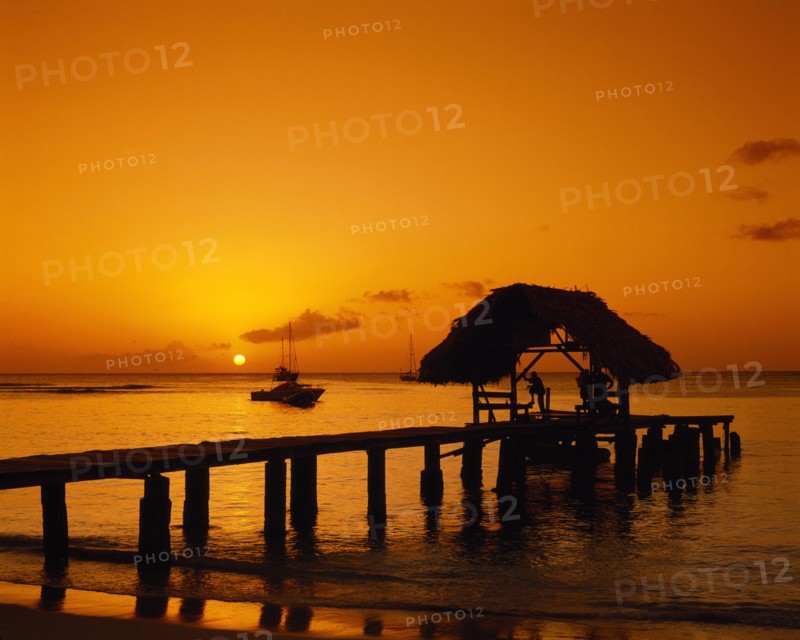 WEST INDIES, Tobago, Pigeon Point, Wooden jet and boat silhouetted at sunset.