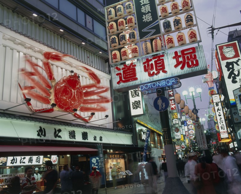 JAPAN, Honshu, Osaka, Dotonbori area at night with illuminated sign and buildings and people walking on the pavement