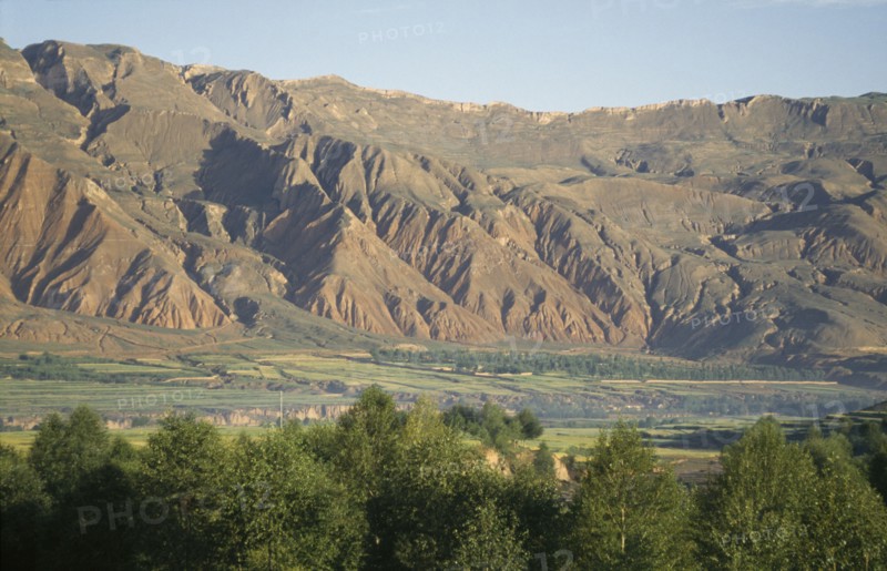 CHINA, Qinghai, General, Mountains behind trees and fields at the edge of the Tibetan plateau