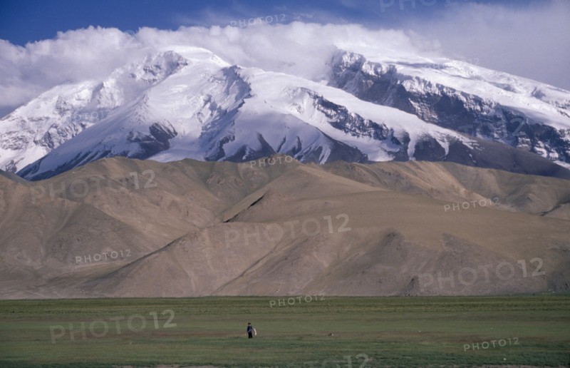 CHINA, Xinjiang , Snow capped mountains near the Pakistan border with man standing in the distance