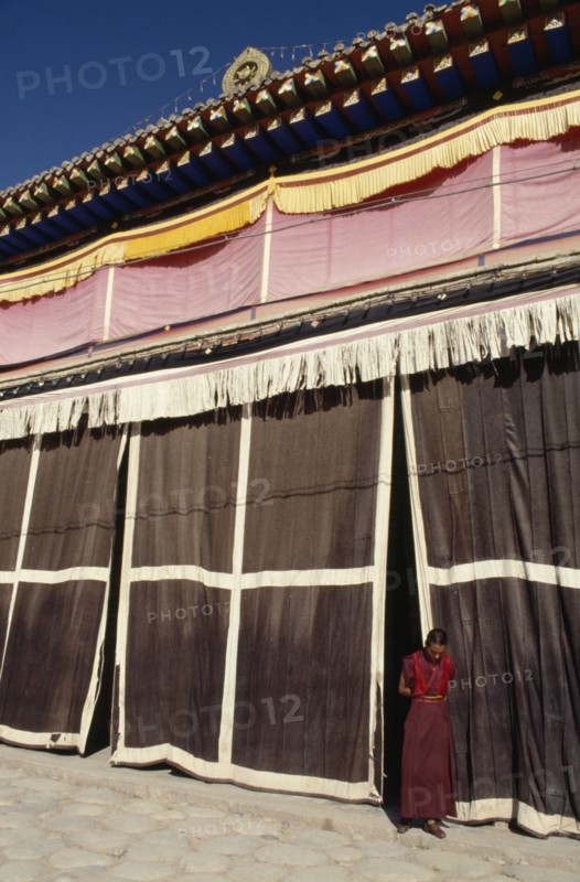 CHINA, Quinghai, Tongren, Monk standing at the entrance to a Tibetan monastery