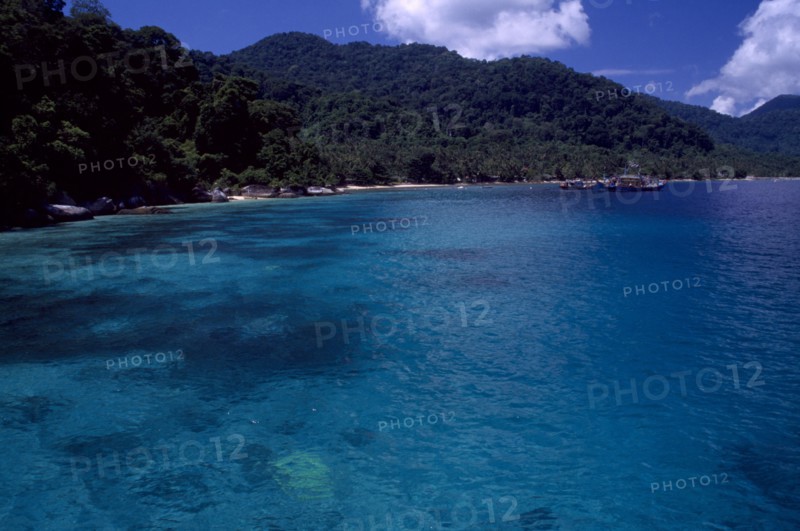 MALAYSIA, East Coast, Pulau Tioman, View from the sea toward the west coast of the island with green hills and boats in the distance