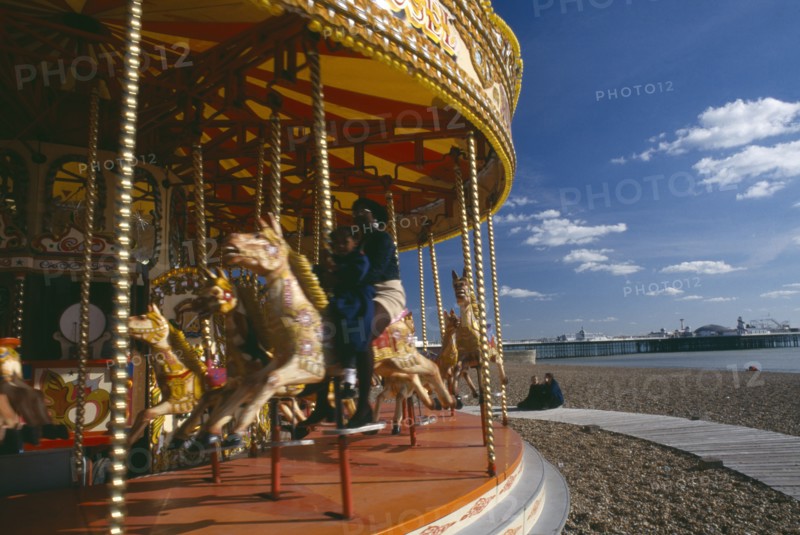 ENGLAND, East Sussex, Brighton, Child and mother sitting on a carousel on the seafront
