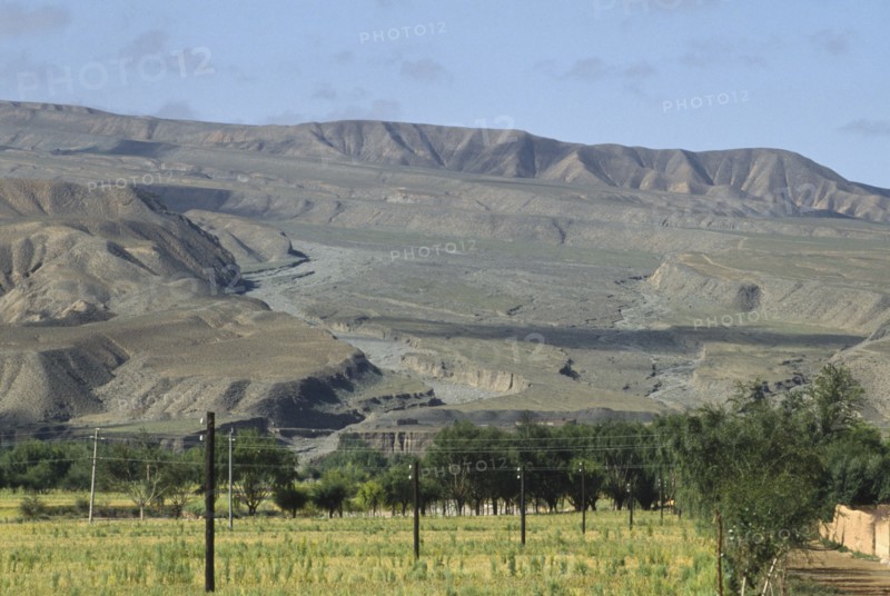 CHINA, Qinghai  , Near Yellow River , Eroded rocks above wheat field in high altitude remote valley