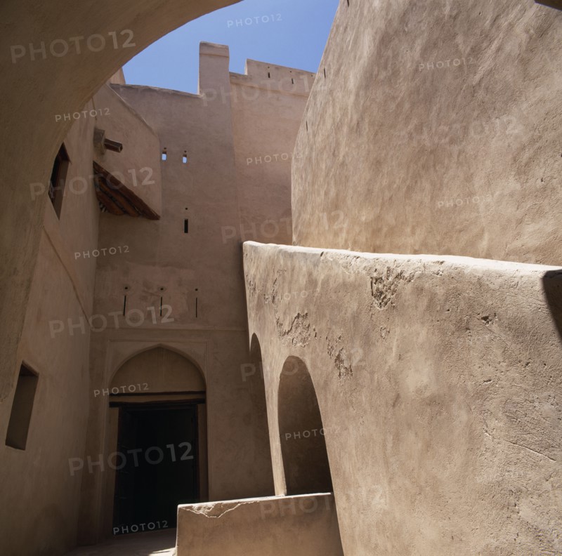 OMAN, Western Hajar, Rustaq, "Fort. Interior view of plain walls, doorway with arch and  blue sky above "