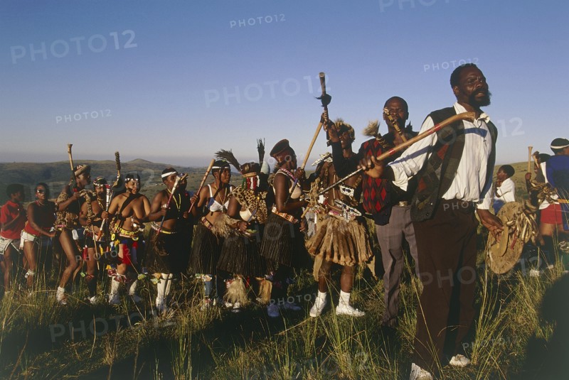 SOUTH AFRICA, KwaZulu Natal, Melmoth, Procession of bride's family at Zulu wedding in colourful dress carrying sticks and dancing