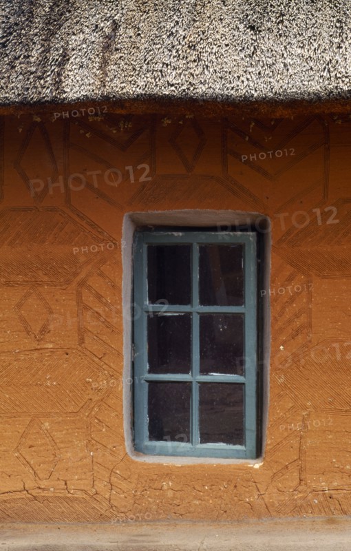 SOUTH AFRICA, Qwa Qwa, Basotho Cultural Village, Detail of typical house with green framed window in recess and orange walls.