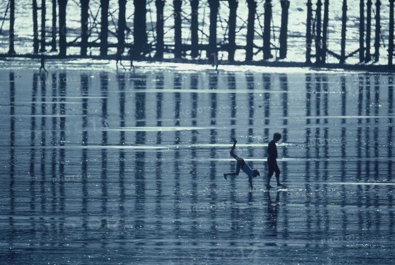 ENGLAND, East Sussex, Hastings, Two boys playing on the beach at low tide beside the pier
