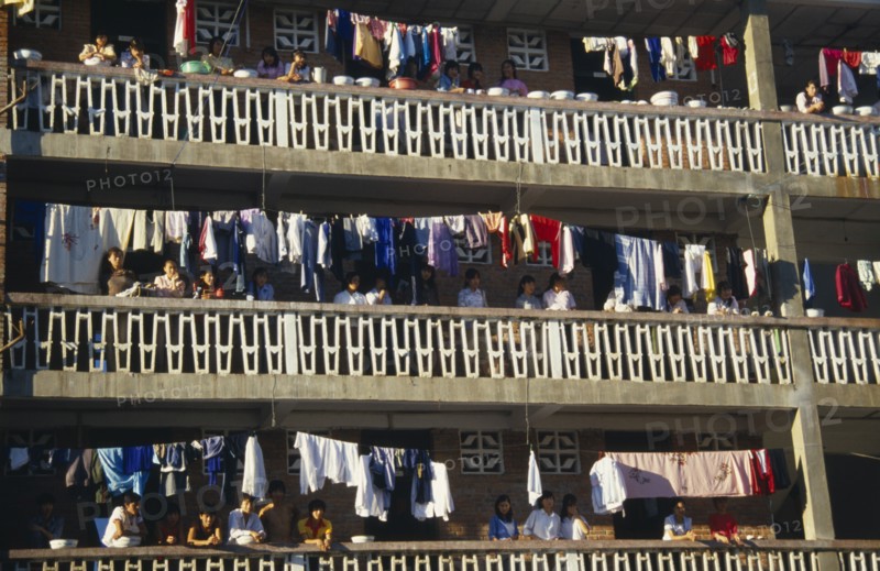 10122697 CHINA Yunan Province Jinghong Laundry hanging on apartment balconies in the Xishuangbana area with residents looking down on street.
