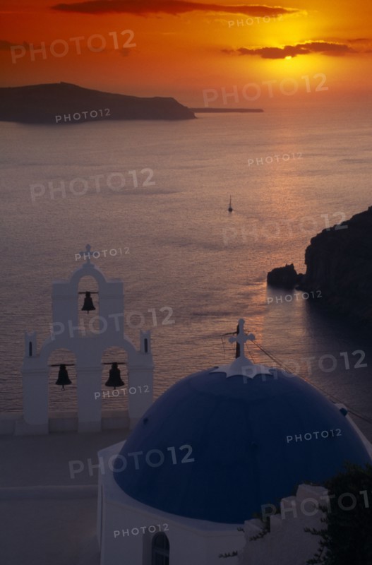 GREECE, Santorini, Thira Church, View across the water at sunset from above the blue and white church domes and bell tower
