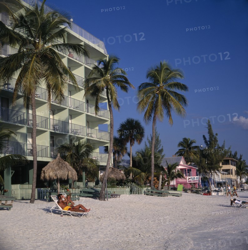 USA, Florida , Fort Myers, Hotels next to sandy beach lined with palm trees and sunbathers on the sand