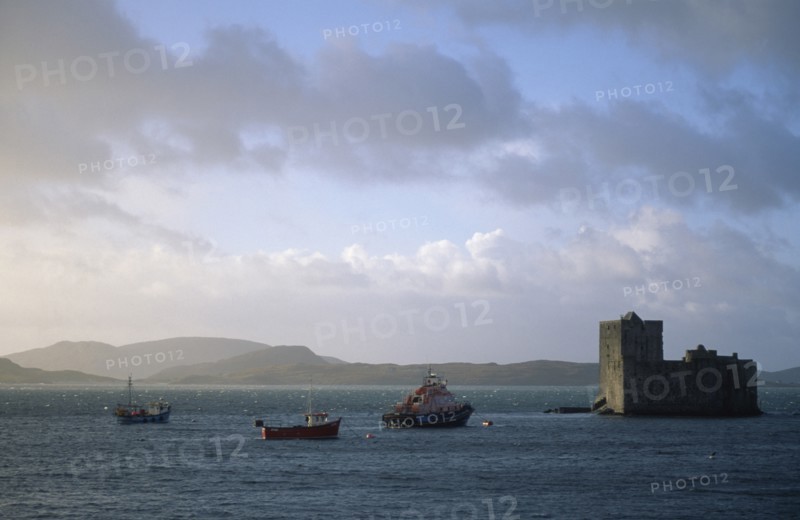 SCOTLAND, Outer Hebrides, Isle of Barra, Castle Bay.  Kisimul Castle overlooking sea and fishing boats.