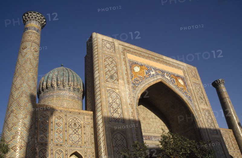 UZBEKISTAN , Samarkand, Registan , "Shir Dor Madrassah, detail of the decorated arch, dome and tower of the Muslim college partially cast in shadow"