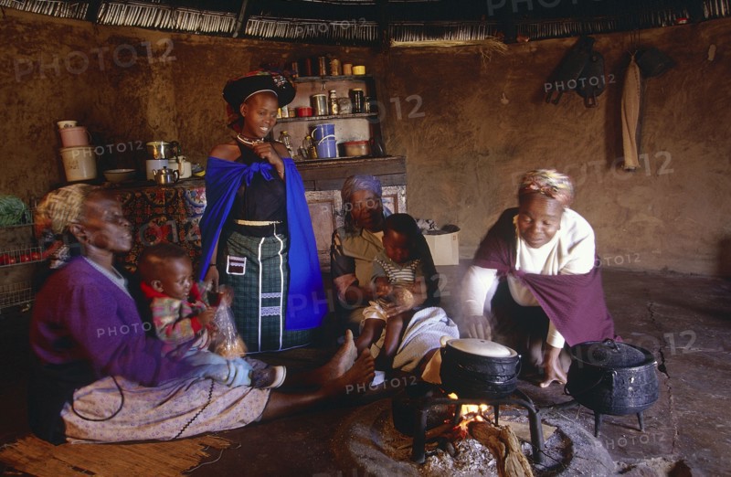 SOUTH AFRICA, Kwa Zulu Natal , Msinga, Zulu women and children cooking inside a Zulu hut or indlu.