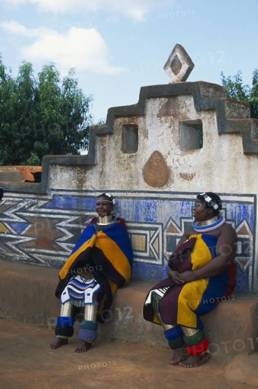 SOUTH AFRICA, Mpumalanga, Middelburg, Botshabelo Ndebele Village (formerly Missionary Station) two local women in traditional dress sitting down.