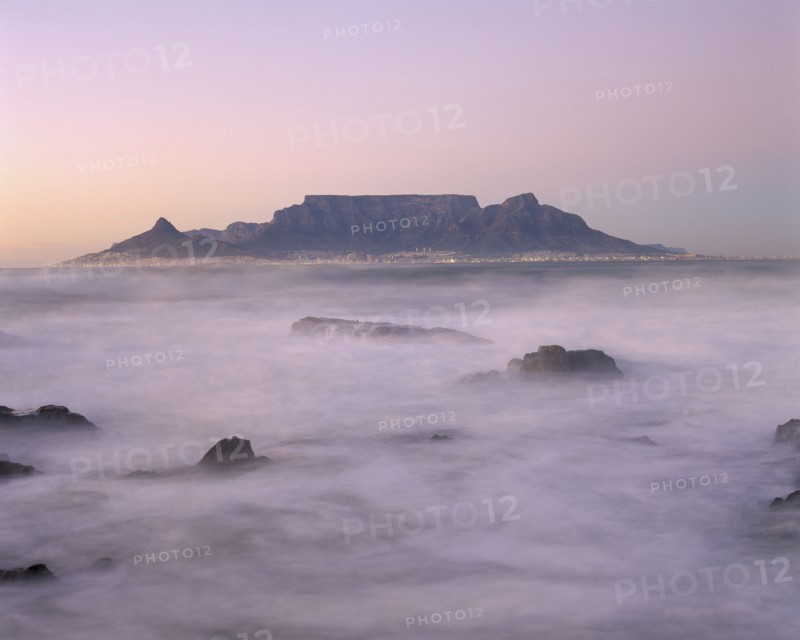 SOUTH AFRICA, Cape Province, Cape Town, View of Table Mountain at dawn taken from Bloubergstrand shore line with heavy mist.