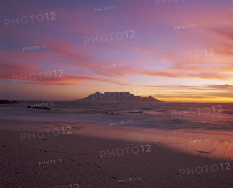 SOUTH AFRICA, Cape Province, Cape Town, View of Table Mountain at dusk taken from Bloubergstrand shore line dramatic sky.