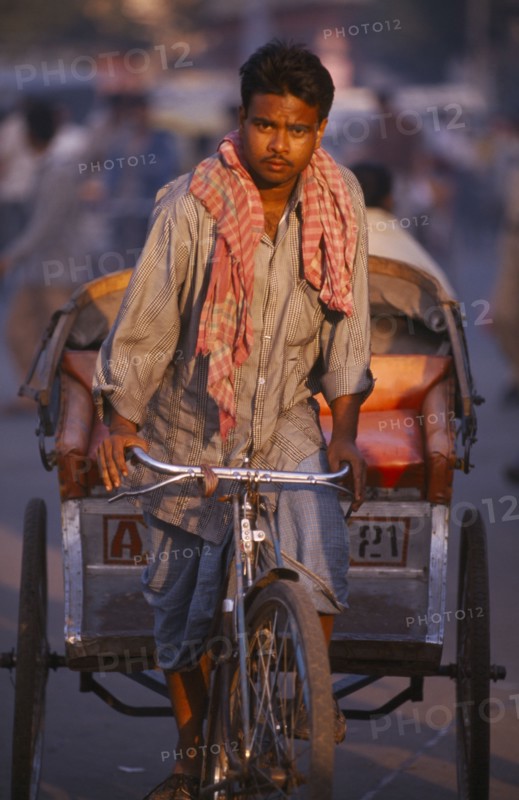 INDIA, Uttar Pradesh, Delhi, Rickshaw driver cycling on the road in the early morning