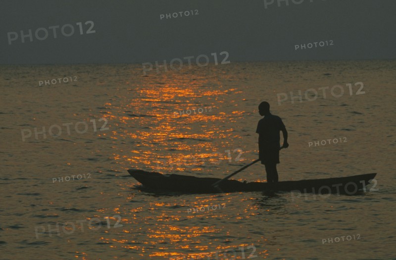 TANZANIA, Lake Tanganyika, Mokoro canoe raft paddler on water at sunset