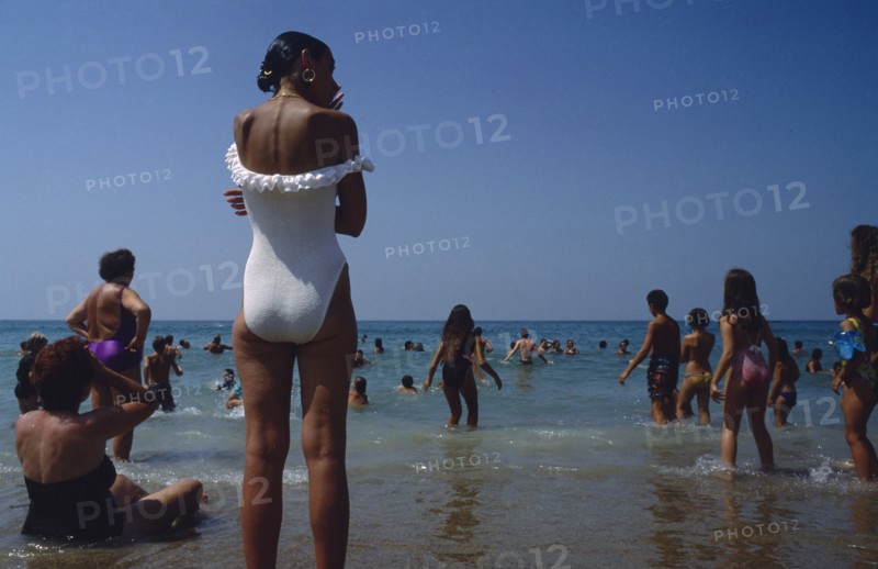 FRANCE, Aquitaine, Pyrenees Atlantiques, Biarritz.  Busy beach scene with people standing and playing in the water.
