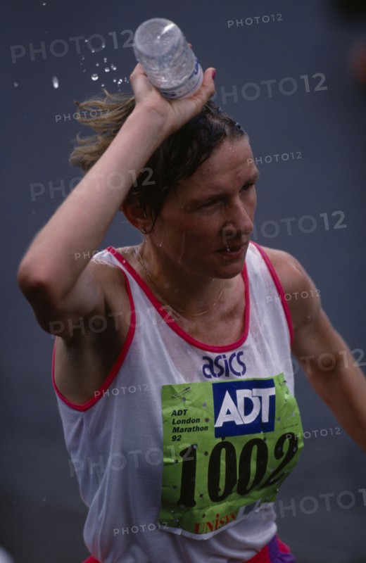 10088209 SPORT Athletics  Marathon Competitor in London Marathon pouring bottle of water over her head to keep cool.