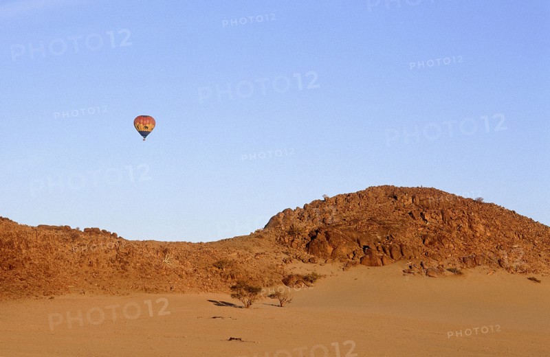 NAMIBIA, Namib Desert, Hot air ballooning above rocky outcrop over sand dunes