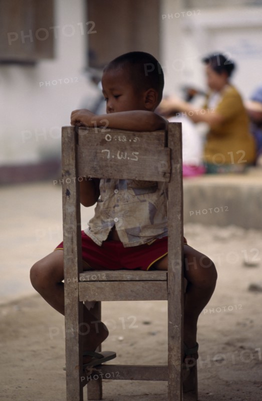 THAILAND, North, Mae Sai , Karen refugee boy sitting on chair