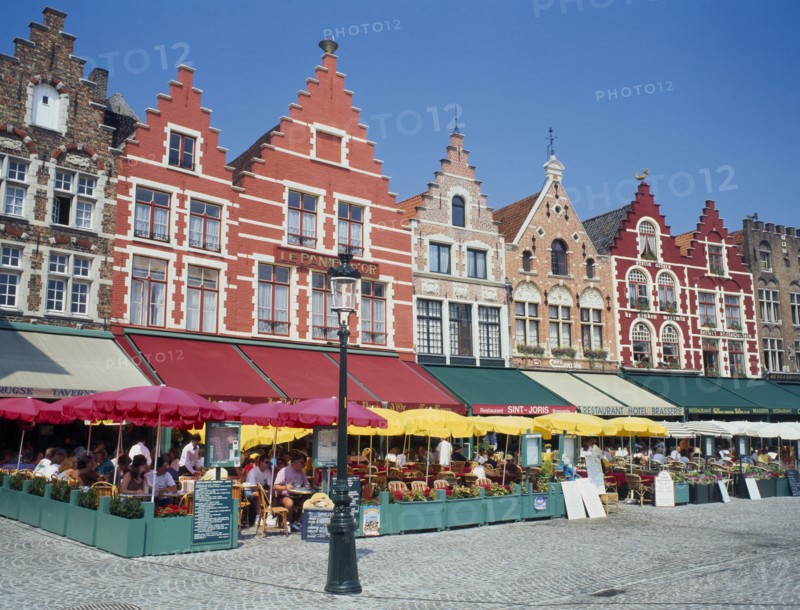 BELGIUM, West Flanders, Bruges, "The west side of the Main Square, Grote Markt, with outdoor restaurants and umbrellas "