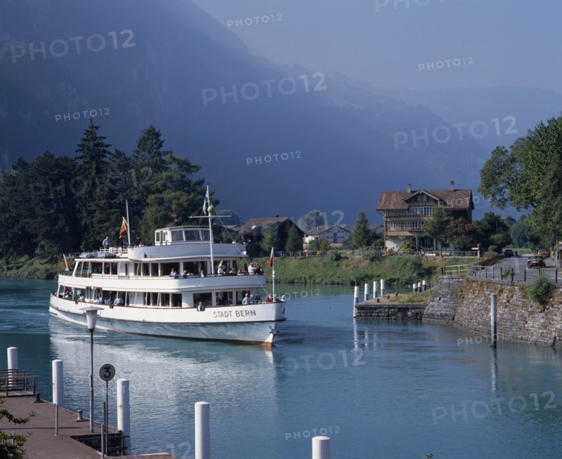 SWITZERLAND, Bern Oberland, Interlaken, White passenger ferry nearing quay with misty wooded mountains in the distance
