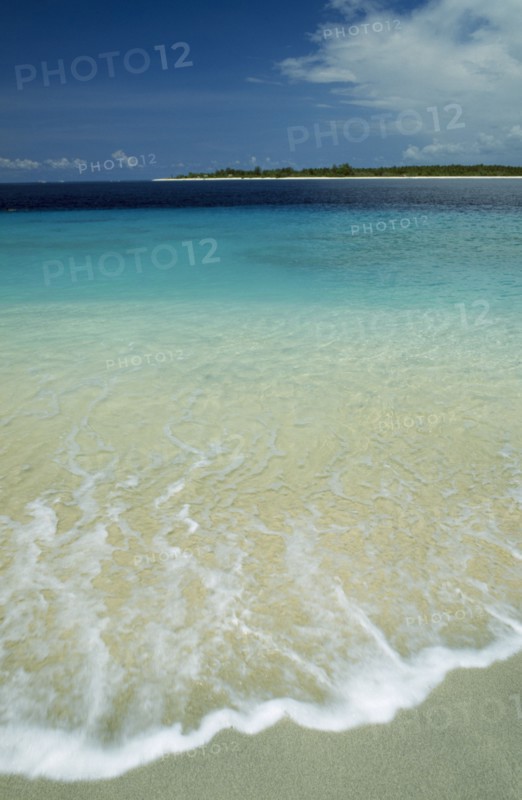 INDONESIA, Lombok, Gili Islands, Gili Trawangan looking towards Gili Meno with gentle waves breaking on the beach