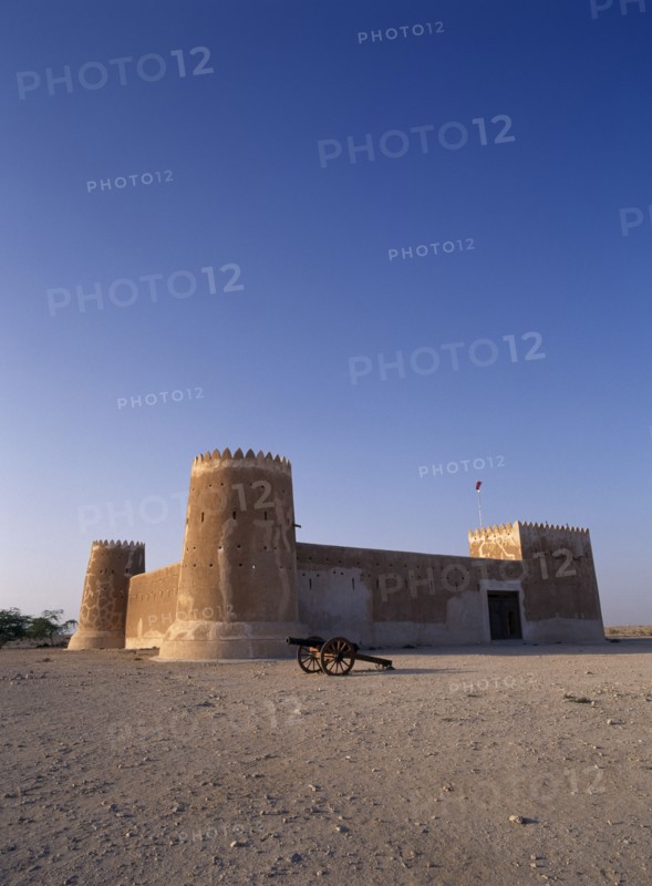 QATAR, Zubara, "Exterior view of a fort with crenellated towers, built in 1938 and used as a police border post, now a museum.  A cannon in the foreground.   "