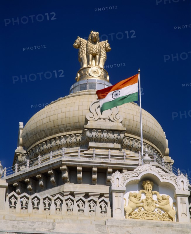 INDIA, Karnataka, Bangalore, "Vidhana Soudha building.  Exterior detail of roof dome, crest, flag and gold statue on top.  Built in 1954 housing the Secretariat and the State Legislature. "