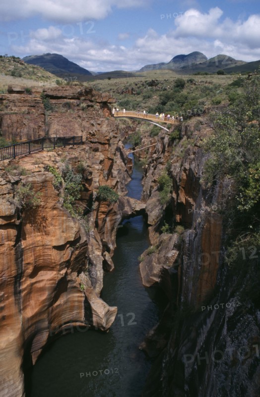 SOUTH AFRICA, East Transvaal, Blydes River Canyon, Bourkes Luck Potholes with people crossing bridge over narrow water filled canyon and mountains in the distance