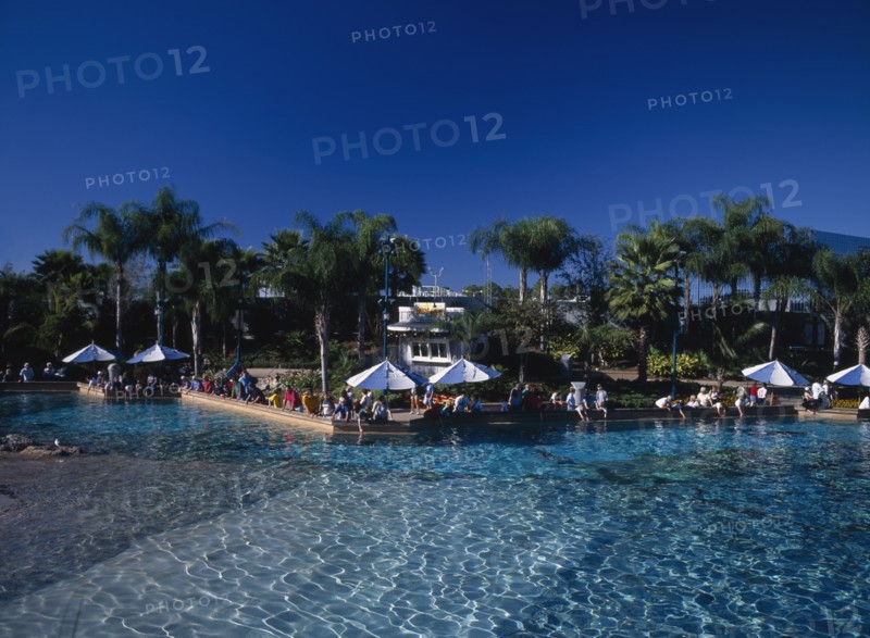 USA, Florida,  Orlando , Seaworld. View across a pool towards visitors gathered along the edge near sun shades