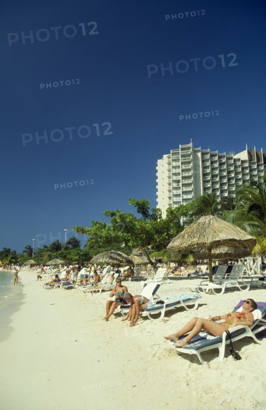 WEST INDIES, Jamaica, Ocho Rios, Sunbathers on the beach with hotel behind