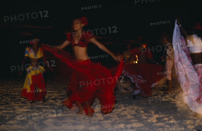 MAURITIUS, Sega Dancers, Women in red costume dancing on the beach at night. Sega is the national dance and music form of Mauritius.
