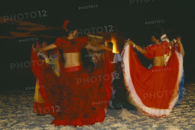 MAURITIUS, Sega Dancers, Women in red costume dancing on the beach at night.  Sega is the national dance and musical form of Mauritius.