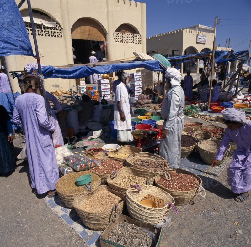 OMAN, Sharqiya, Sanaw, Souk with local people around stalls with spices displayed on ground in baskets