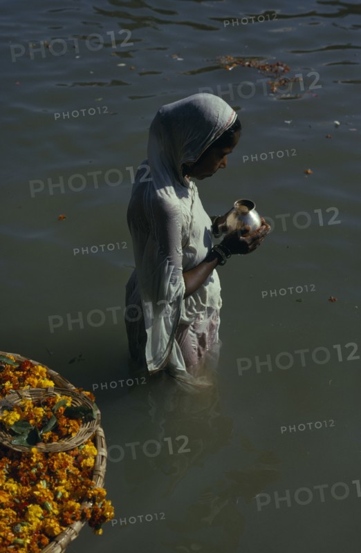 INDIA, Uttar Pradesh, Varanasi , Hindu woman praying waist deep in the water of the River Ganges.