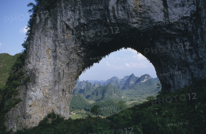 CHINA, Guangxi, Near Guilin, View through natural rock archway near the Li River framing mountainous landscape beyond