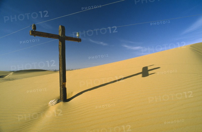EGYPT, Western Desert , Telegraph pole almost covered by sand dune.