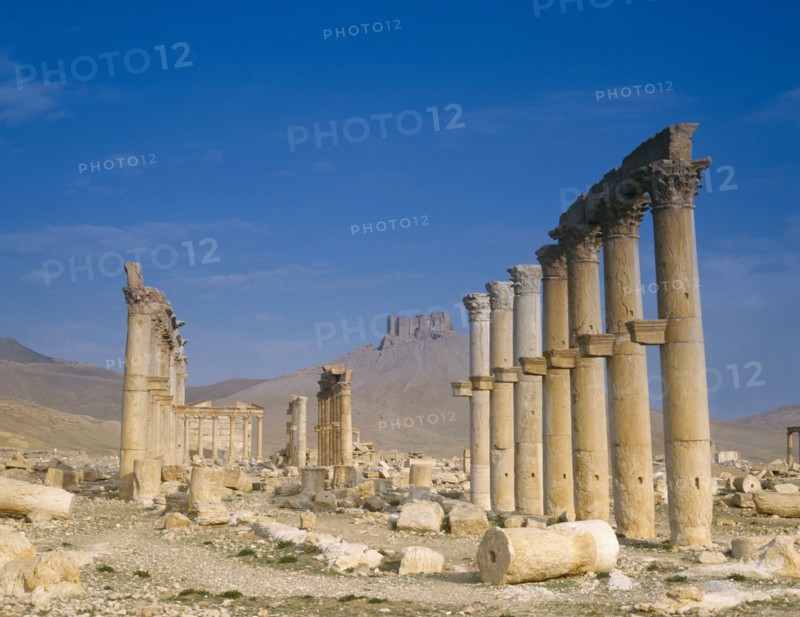 SYRIA, Central, Tadmur, "Monumental Arch, columns and fallen masonry with fort on hillside beyond. "